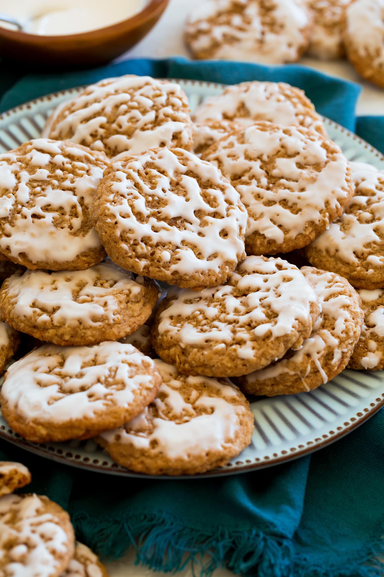 Iced oatmeal cookies stacked together on serving plate.