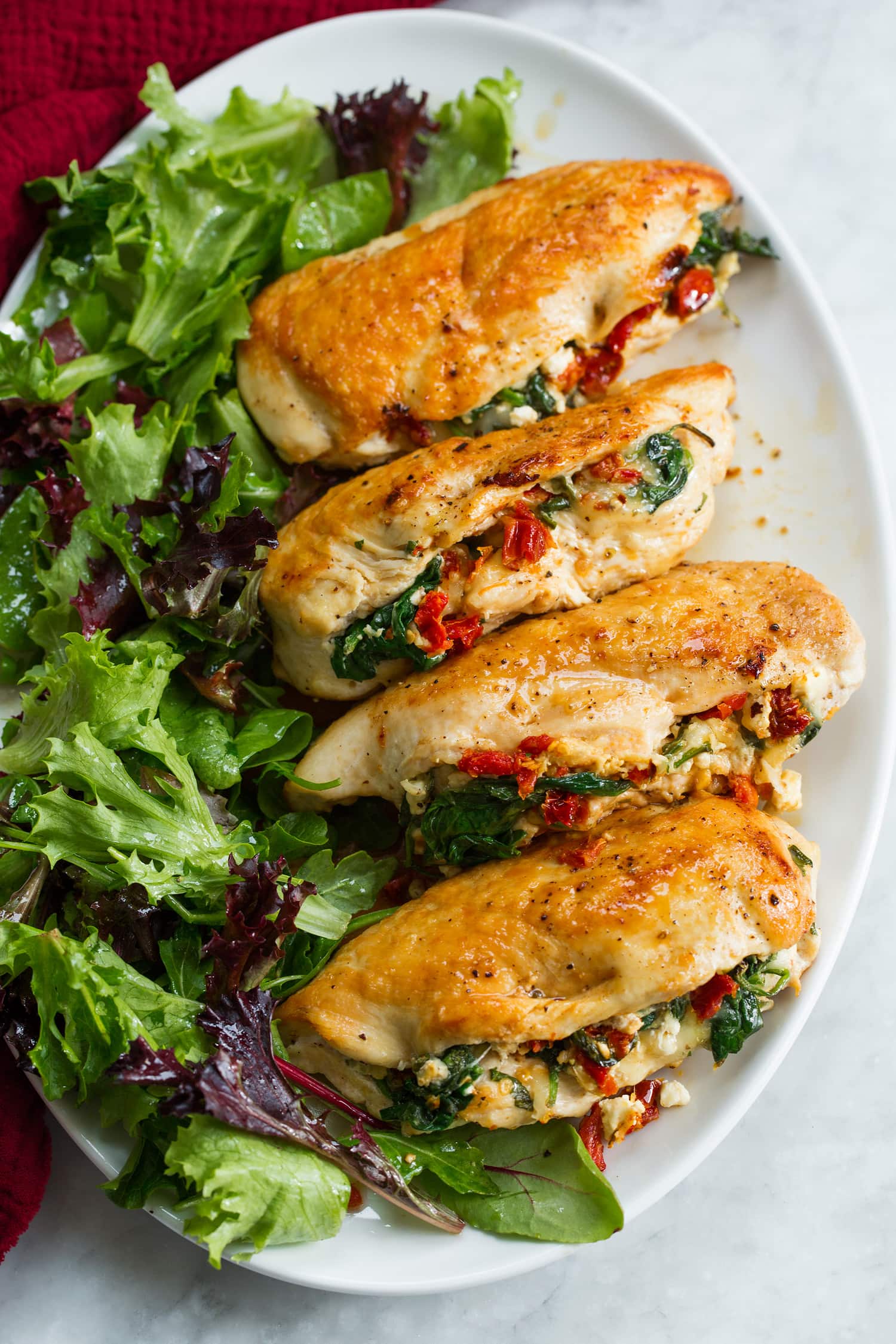 Stuffed chicken breasts on a platter with a side salad.