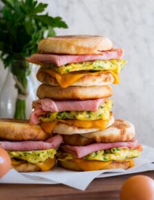 Stack of breakfast sandwiches with eggs, meat and cheese.