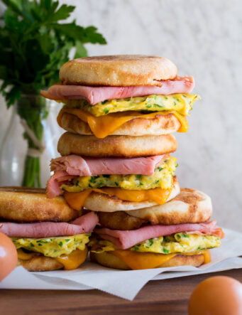 Stack of breakfast sandwiches with eggs, meat and cheese.