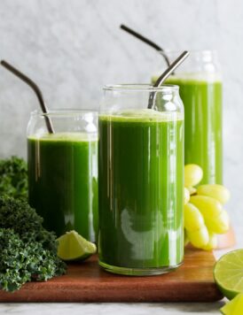 Three servings of green juices made with different greens including spinach, romaine lettuce and kale. Also includes cucumber, grapes, apples, celery, broccoli, lime and ginger.