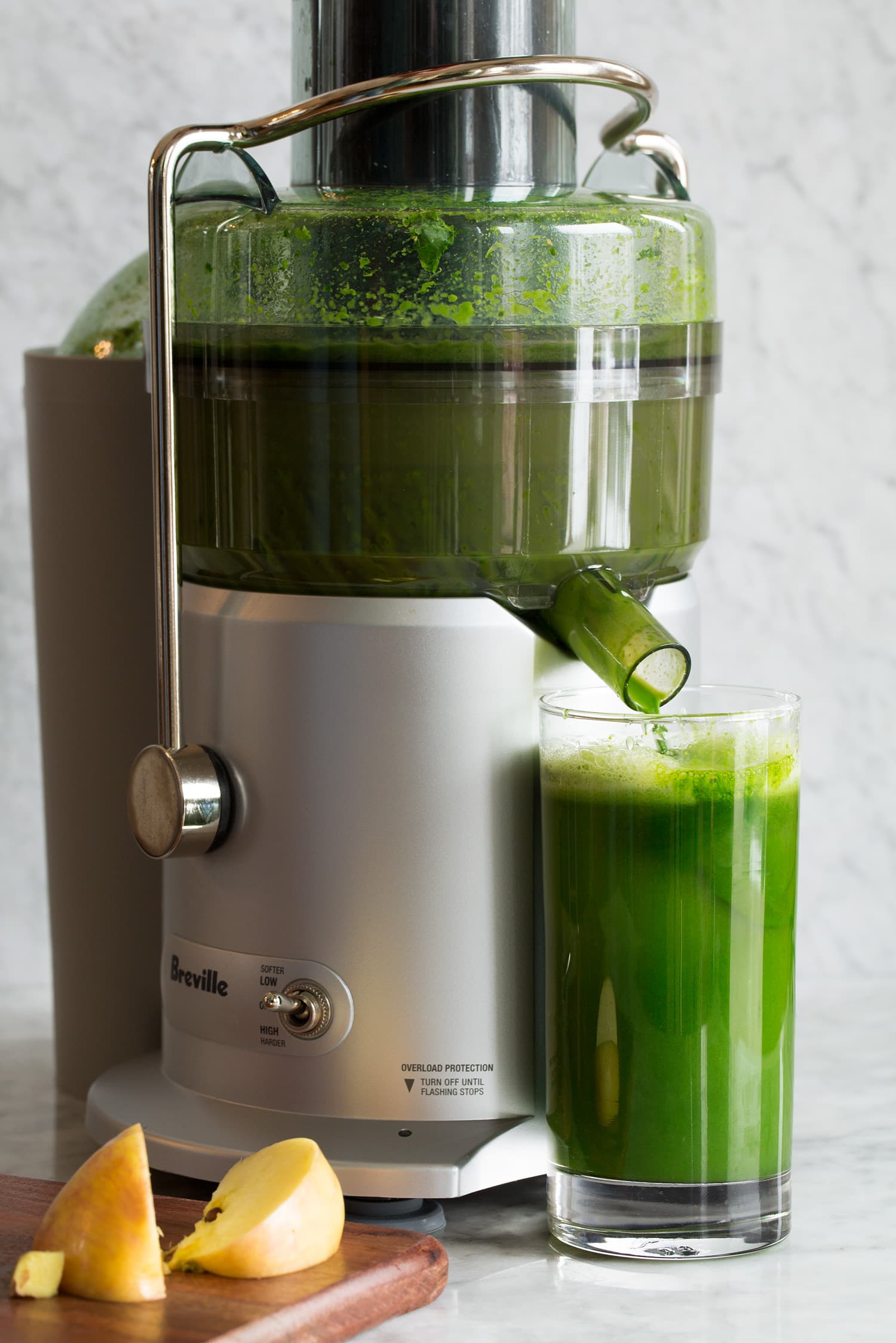 An electric juicer making green juice.
