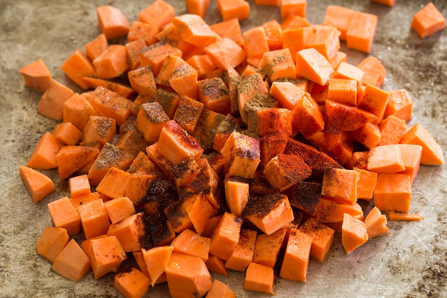Sweet potatoes with spices before tossing.