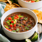 Serving of homemade black bean soup topped with tomatoes, avocado and cilantro.