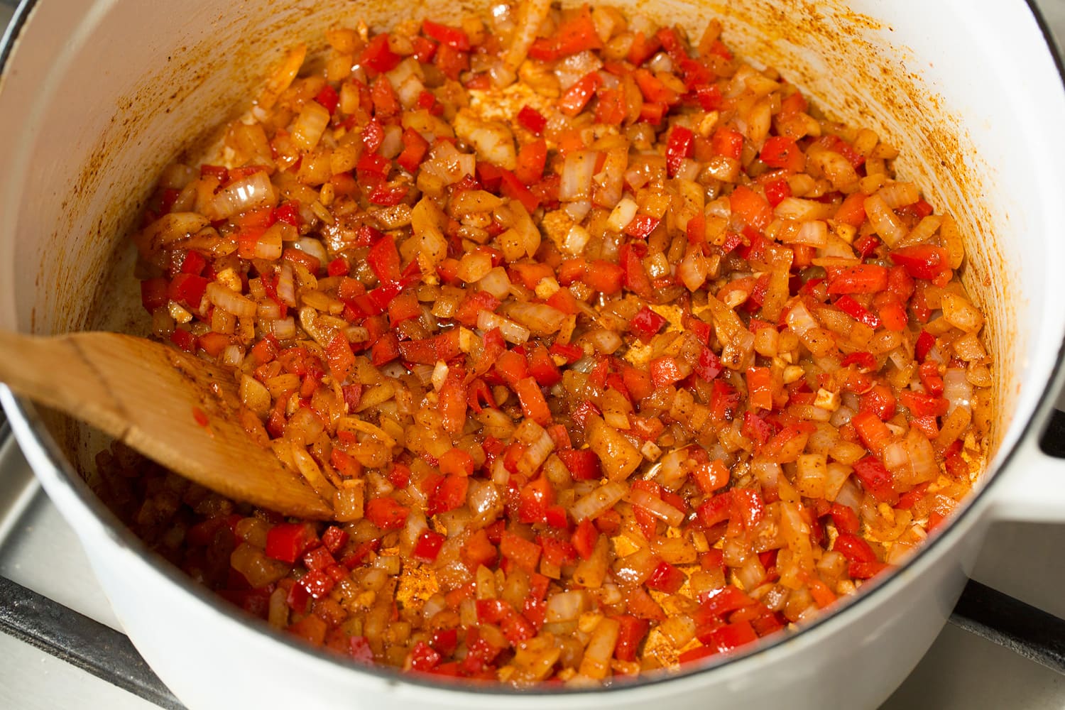 Cooked chopped peppers and onions with spices in a pot.