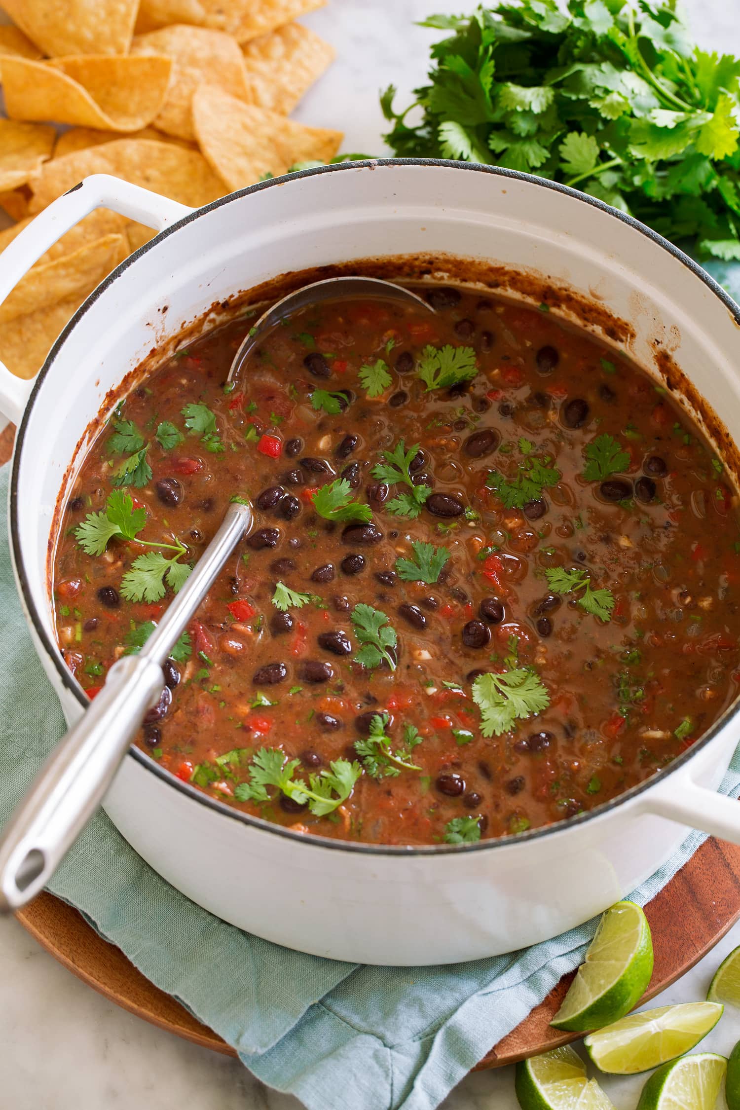 Soup with black beans, bell pepper, tomatoes, bacon, spices and cilantro in pot.