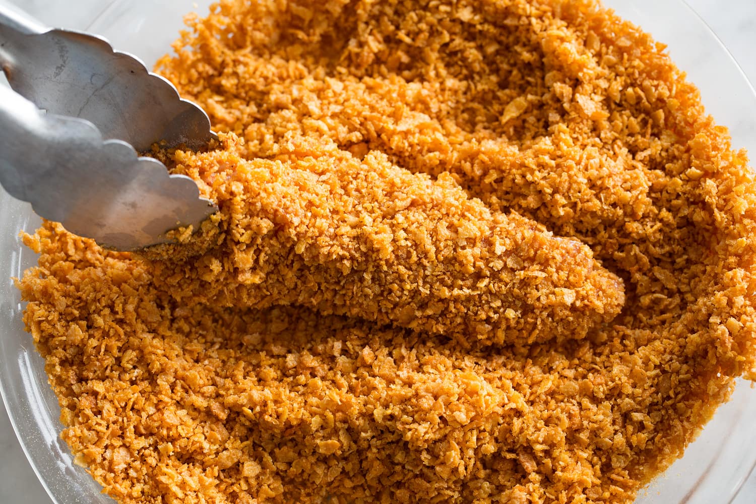 Covering chicken in crushed cornflakes.