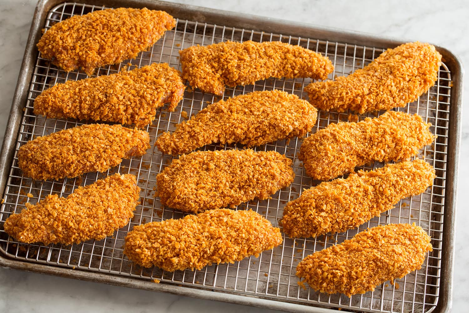 Chicken strips shown on a wire rack and baking sheet before baking.