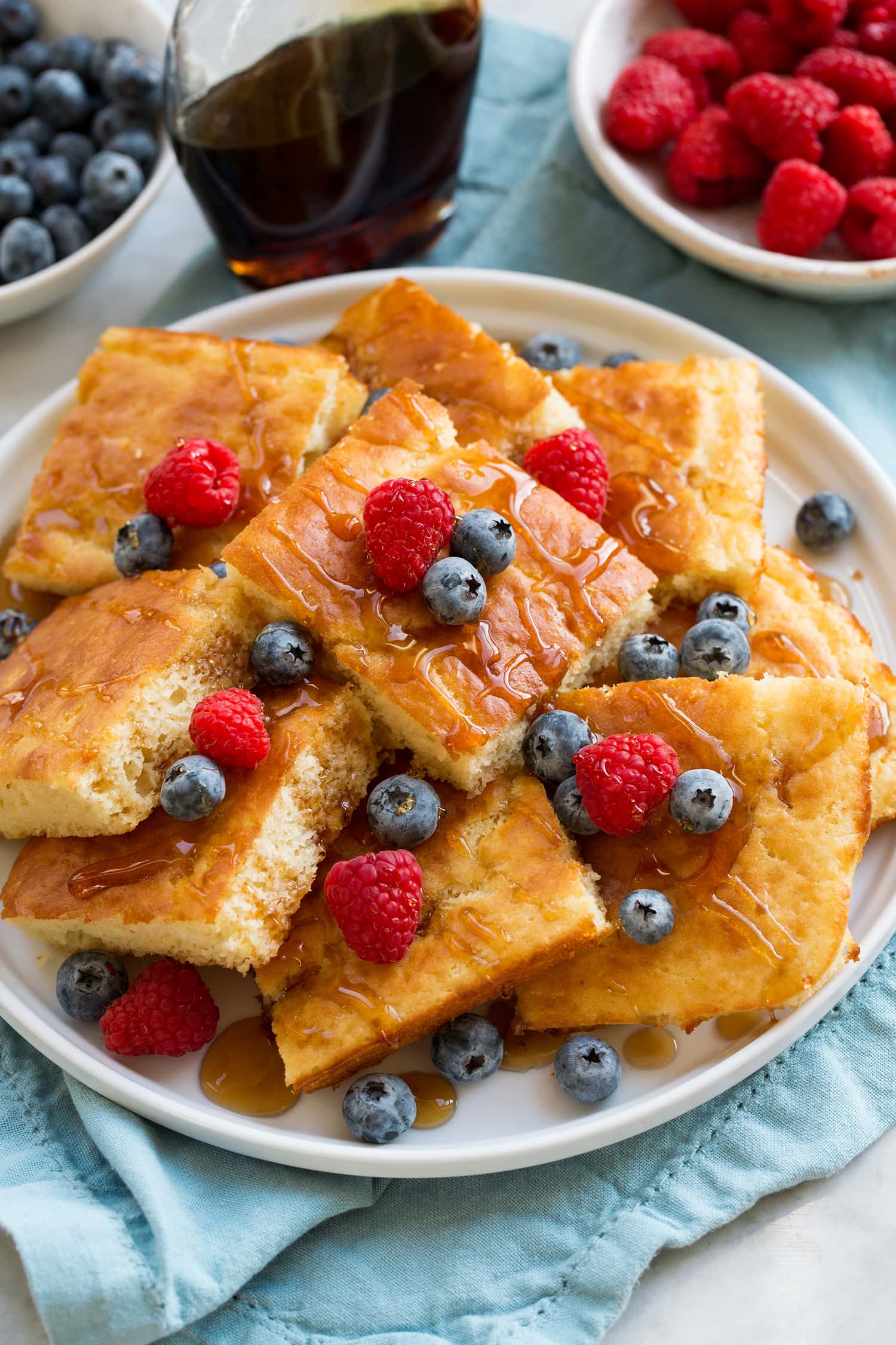Slices of sheet pan pancakes piled with fruit.