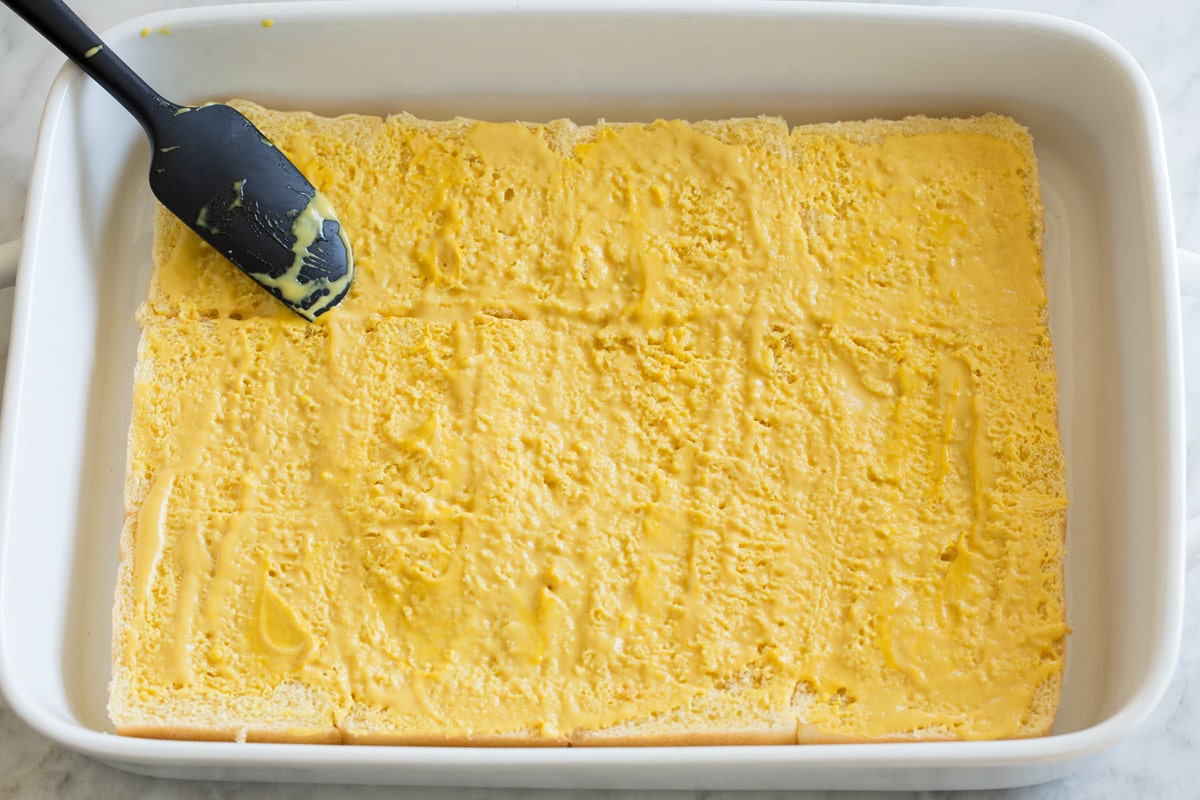 Spreading mustard mixture over roll halves.