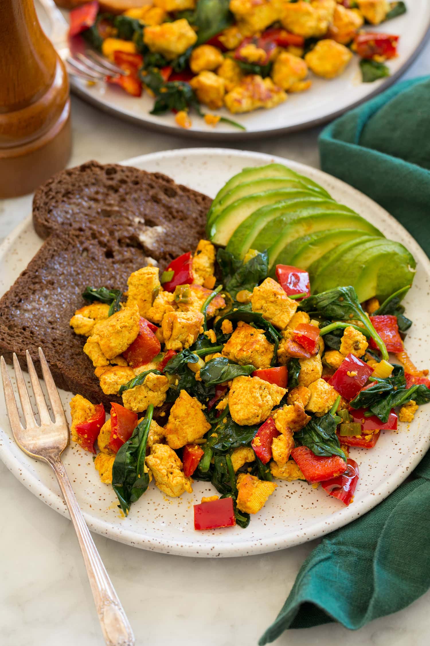 Tofu scramble shown with serving suggestions of avocado and whole grain toast.