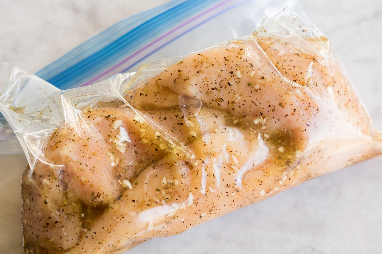 Chicken soaking in marinade in ziplock bag.