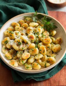 Pan fried gnocchi shown with parmesan and parsley garnish.