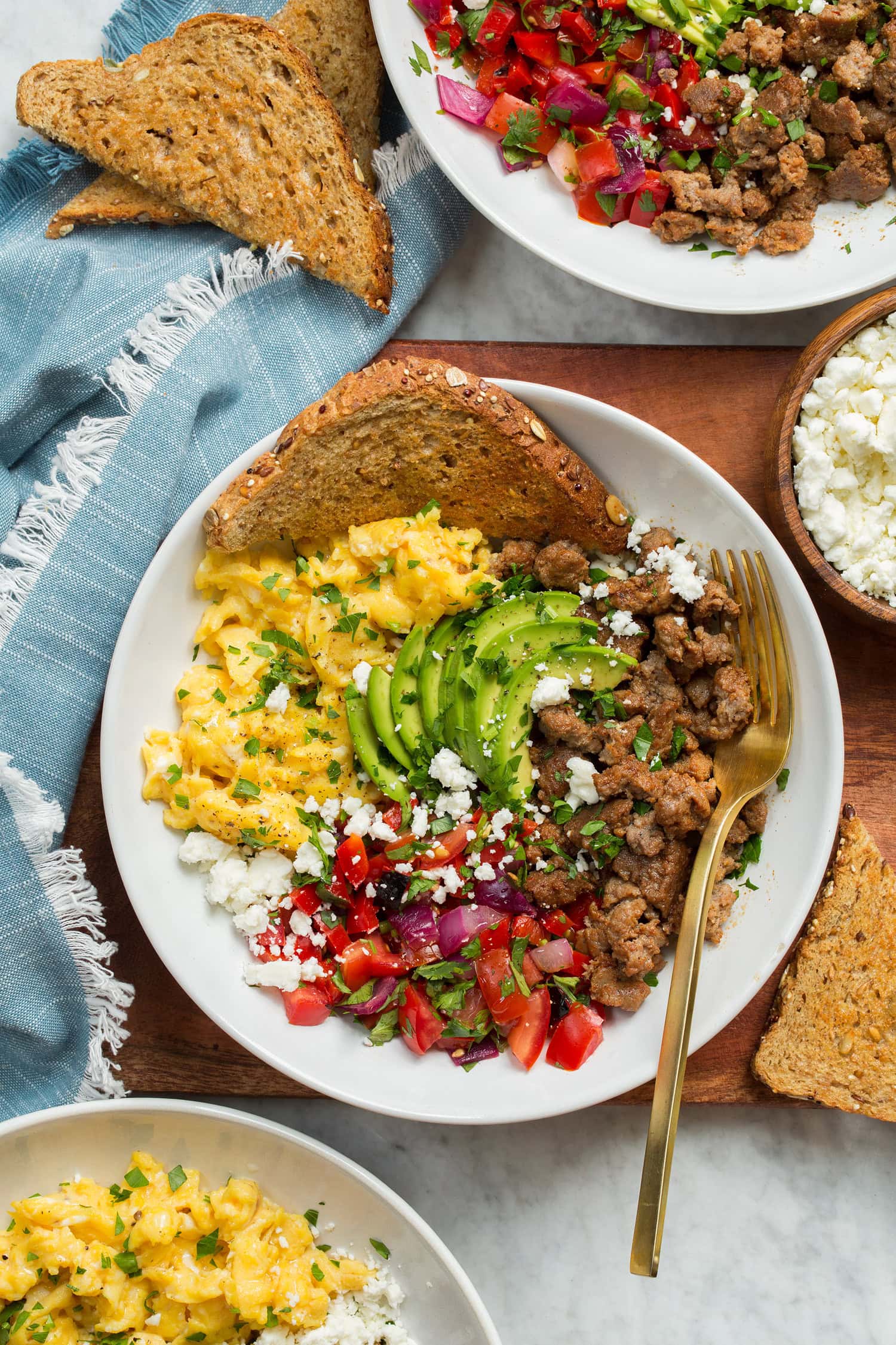 Viršutinės pusryčių dubenėlio nuotrauka ant medinio dėklo su mėlynu audiniu į šoną.