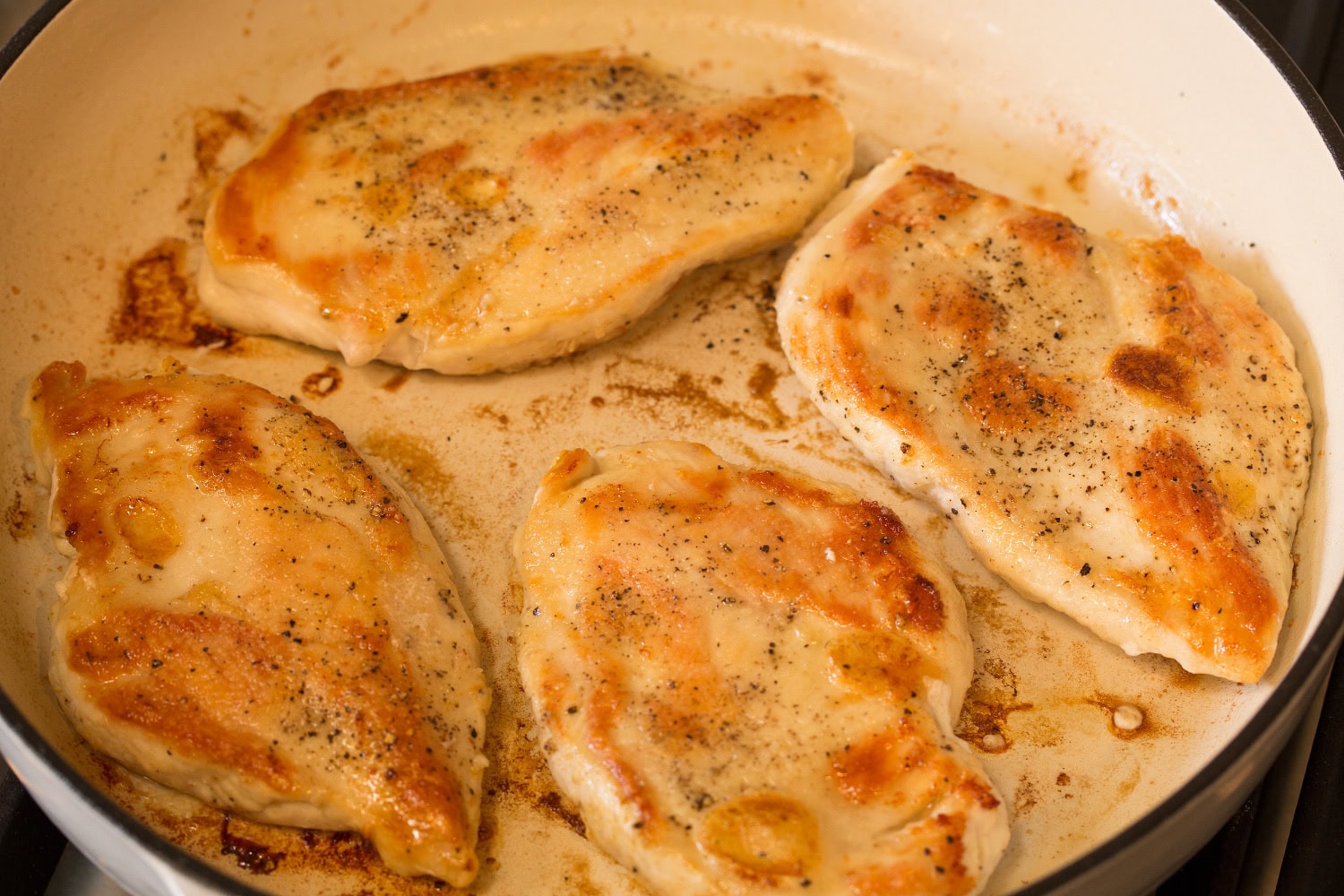 Browned chicken breasts in skillet.