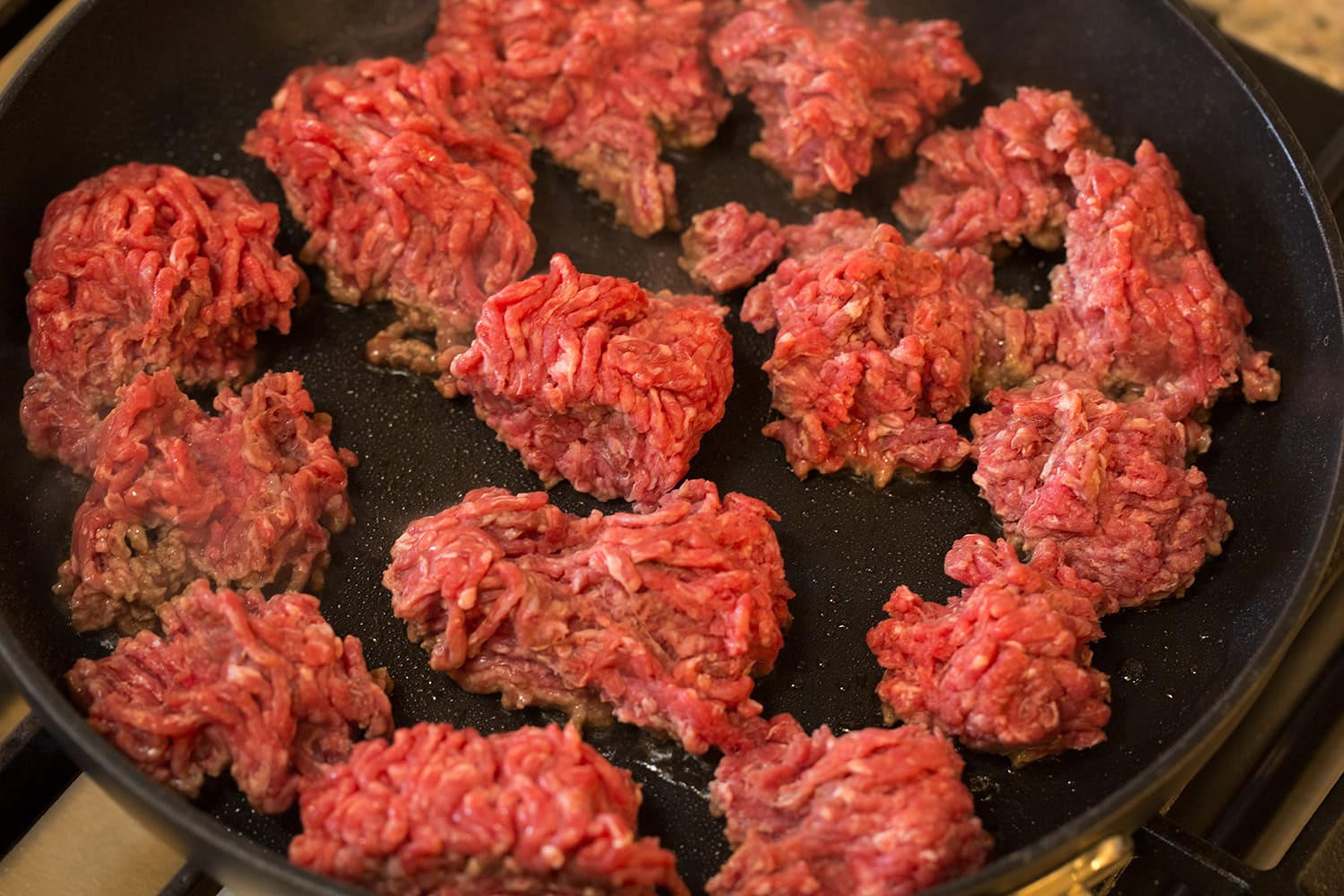 Searing ground beef in chunks in a skillet.
