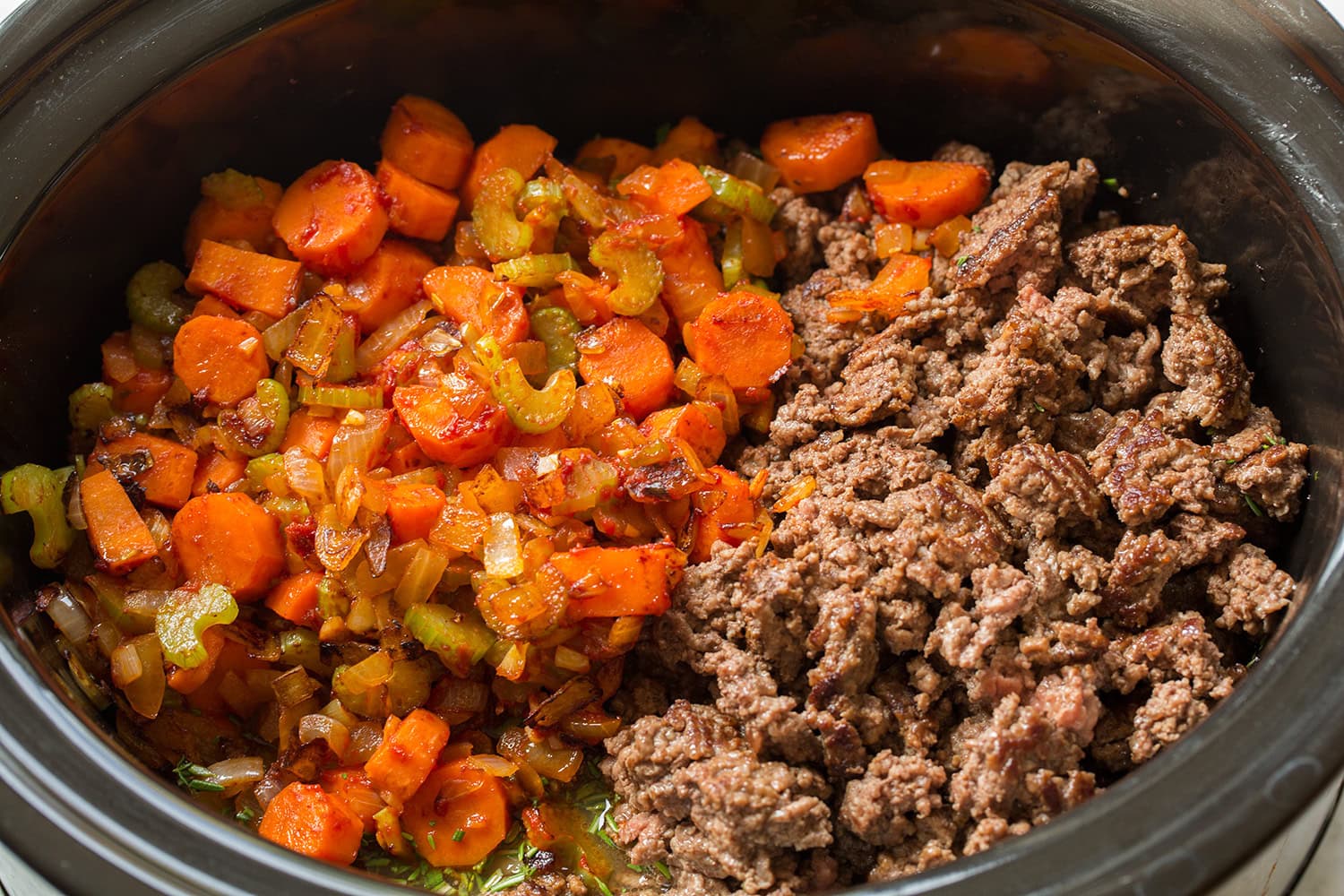 Cooked vegetables and browned beef added to slow cooker.