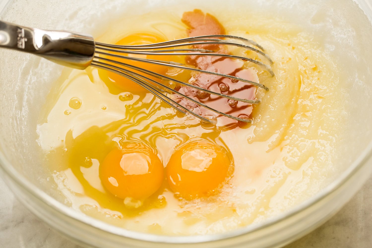 Blending eggs and vanilla into melted butter sugar mixture.