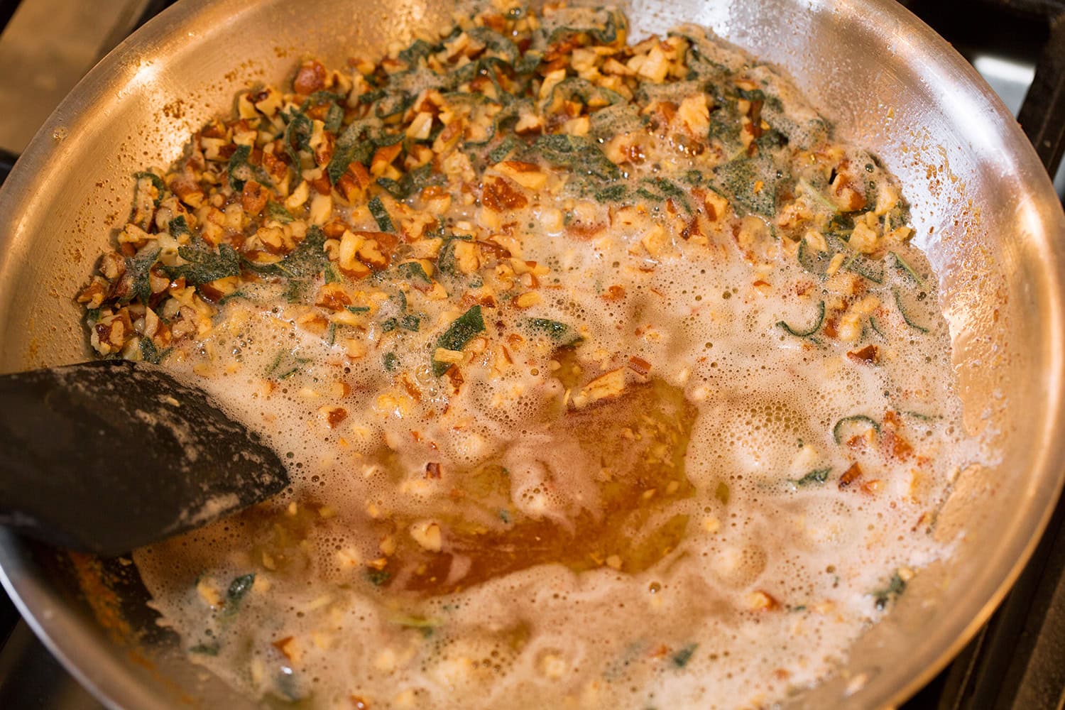 La sauce à la sauge et au beurre noisette dans une poêle en acier inoxydable sur la cuisinière illustrée est terminée.