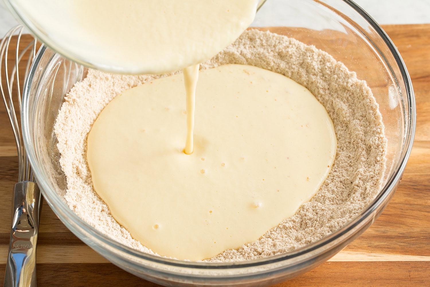 Pouring liquid mixture into dry mixture for pancakes.