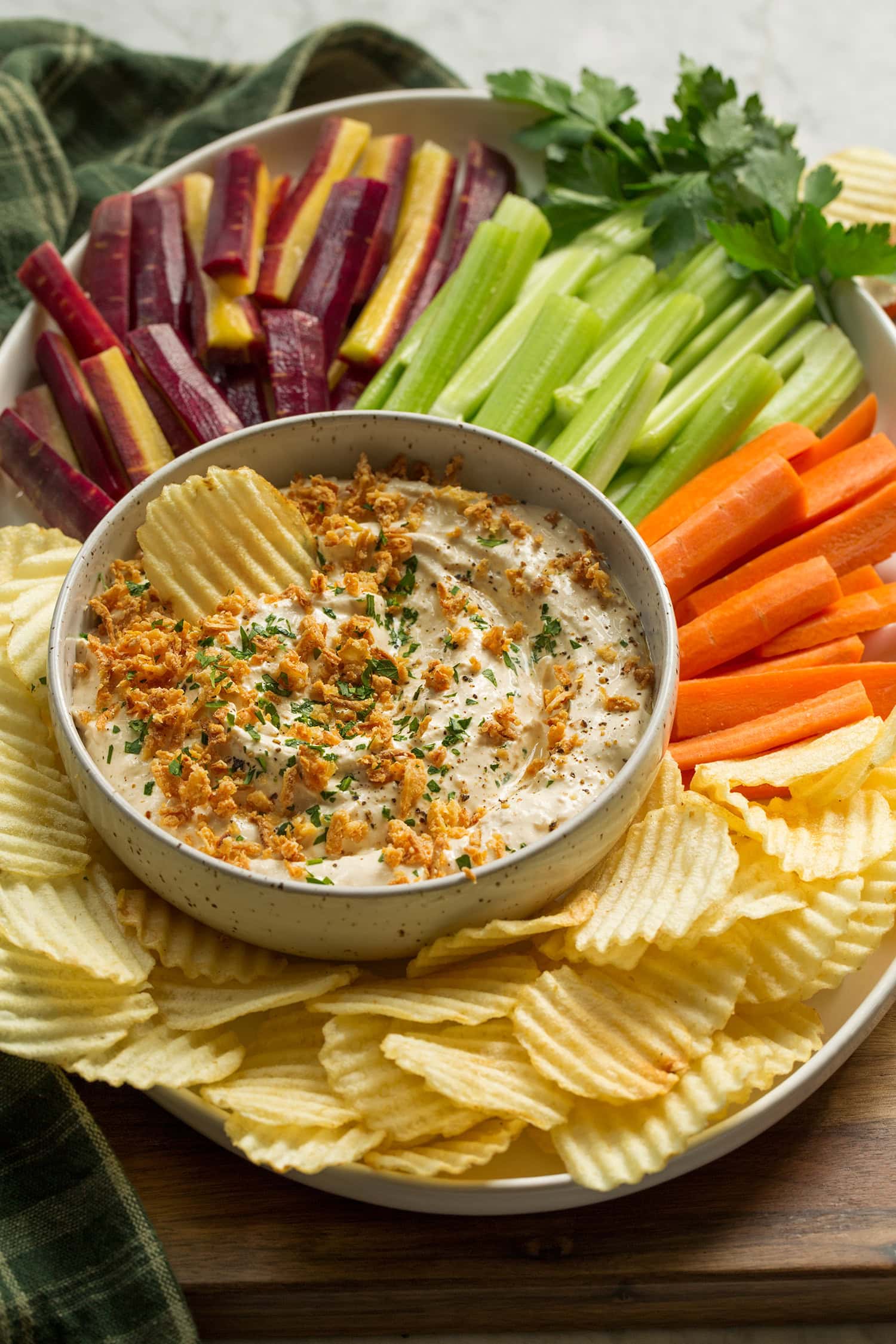 Les oignons français faits maison sont jetés dans un bol sur une assiette avec des carottes, du céleri et des chips.