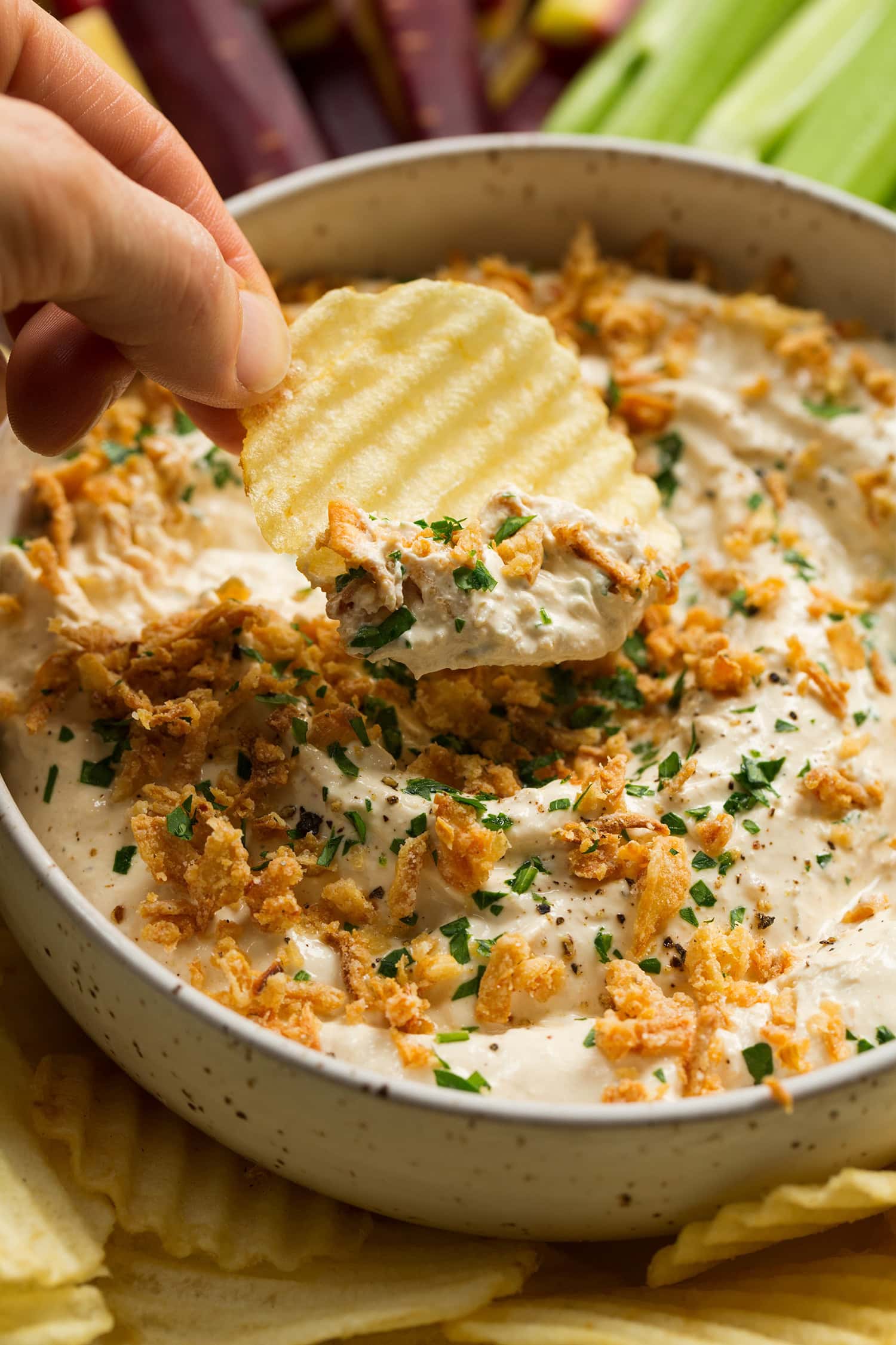 Gros plan de chips de pommes de terre trempées dans une sauce à l'oignon française maison.