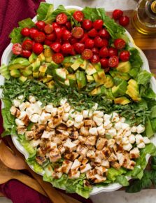 Caprese chopped salad with grilled chicken, avocado, tomato, fresh mozzarella, and basil shown from overhead.
