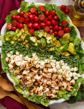 Caprese chopped salad with grilled chicken, avocado, tomato, fresh mozzarella, and basil shown from overhead.
