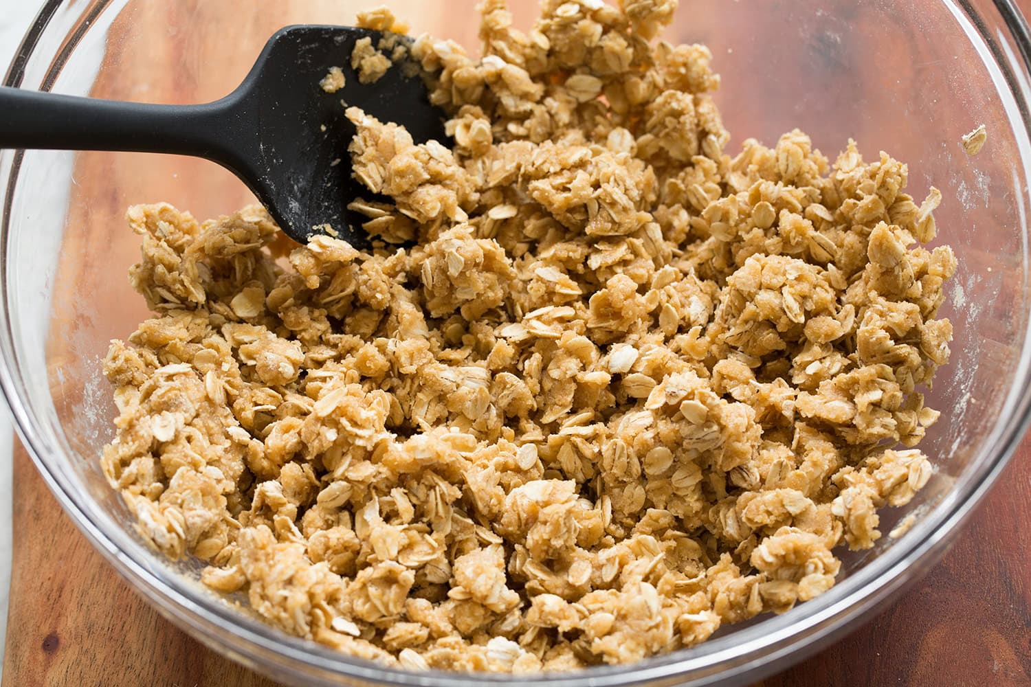 Oatmeal crumb mixture shown after being hydrated and mixed with melted butter using a spatula.