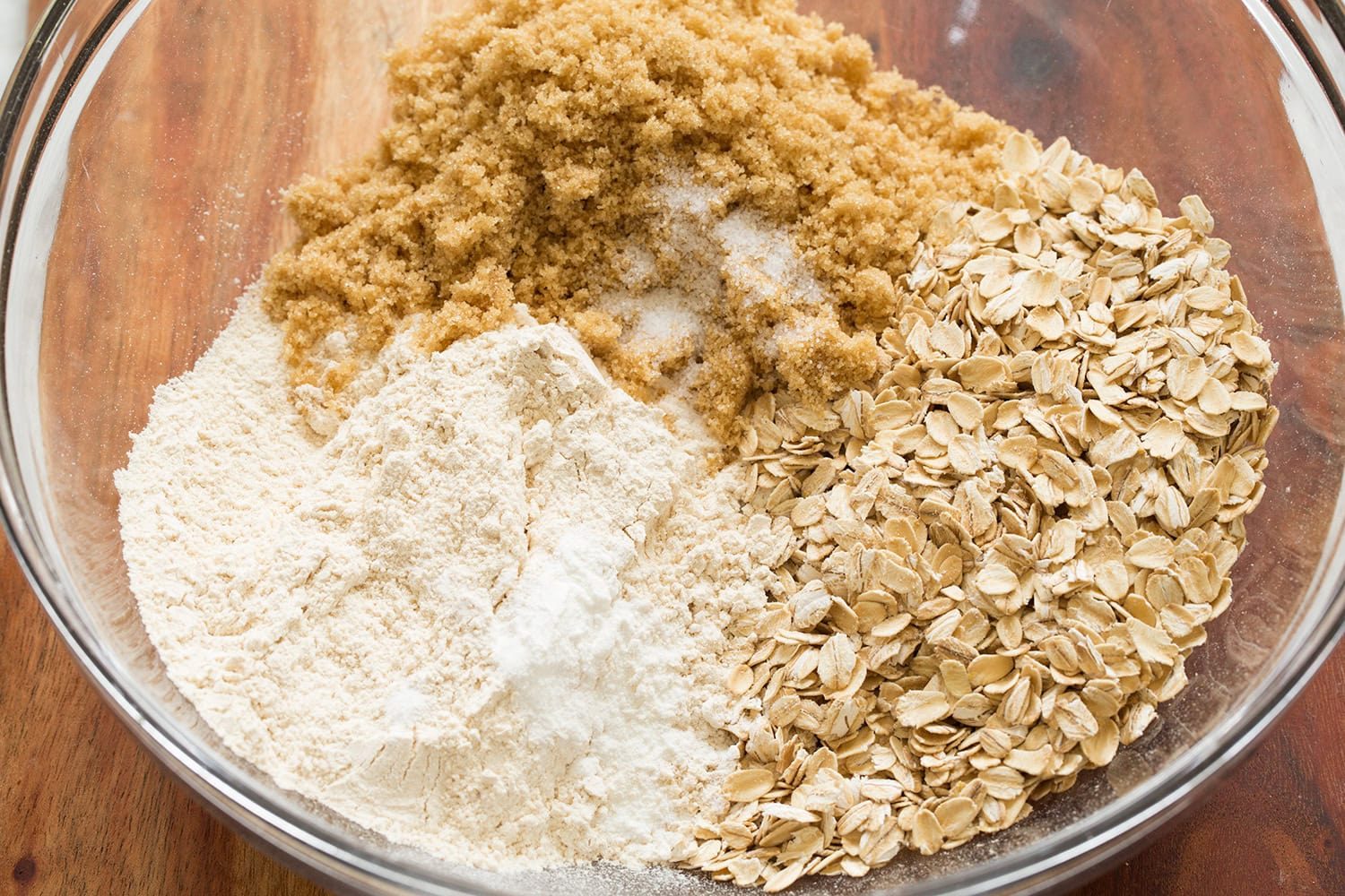 Oats, whole wheat flour, brown sugar and baking powder in a glass mixing bowl shown before mixing.
