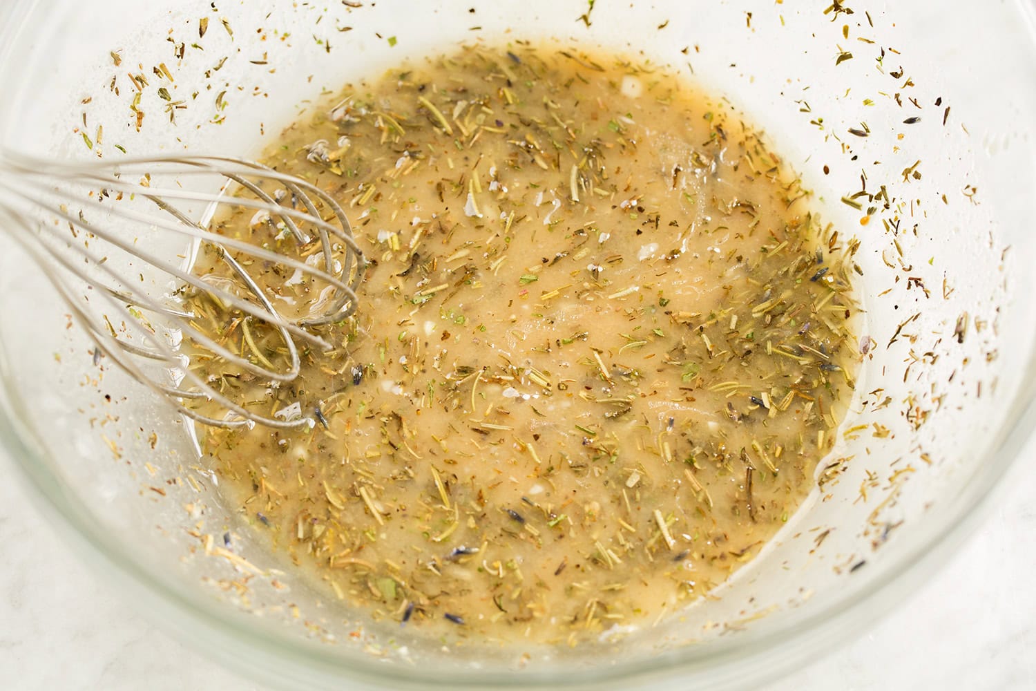 Chicken marinade shown in glass mixing bowl after whisking ingredients.