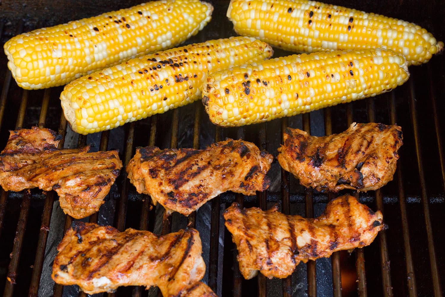 Street Corn Chicken Rice Bowl Chicken thighs and corn shown on the grill after cooked through.