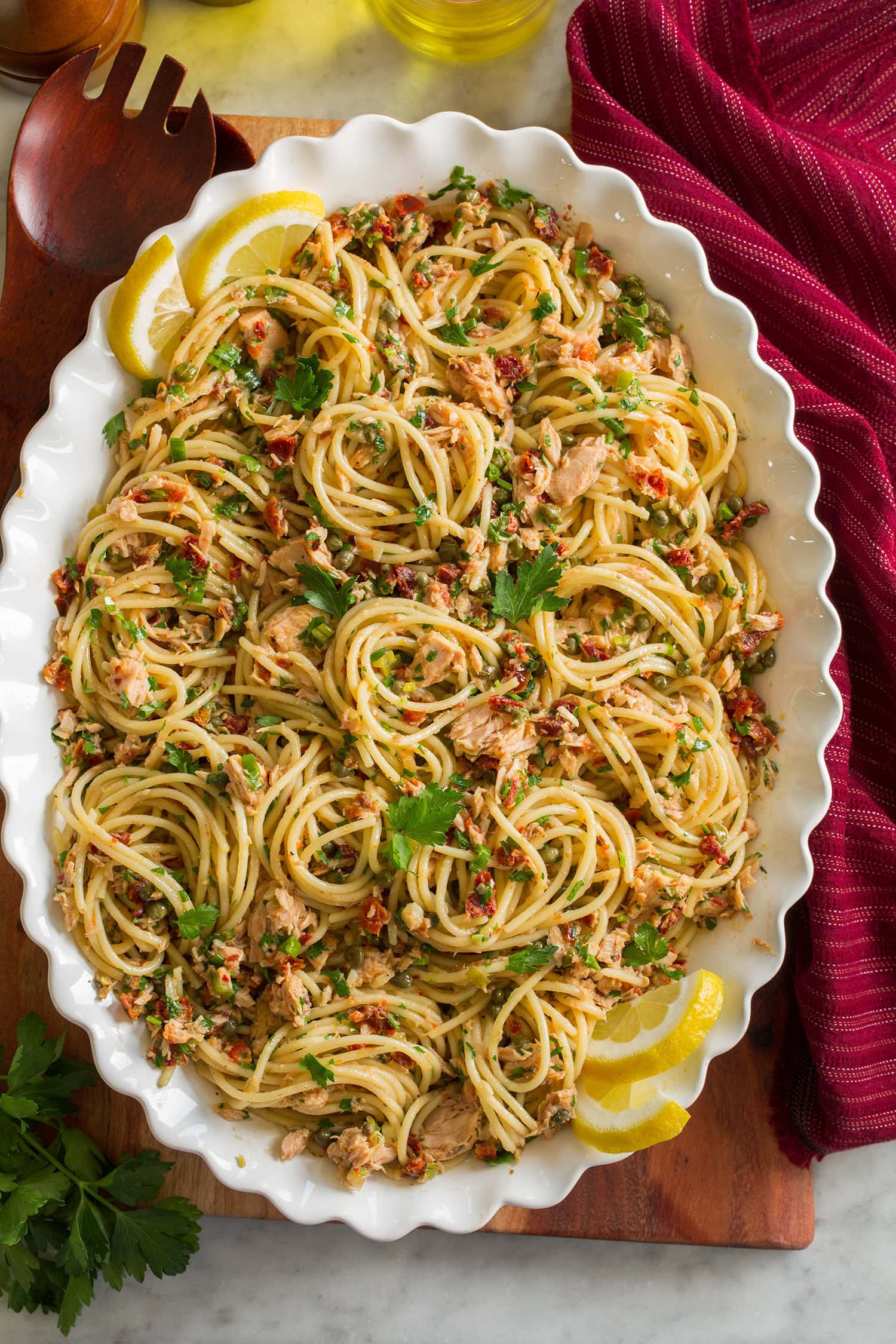 Tuna Pasta Overhead photo of tuna pasta made with spaghetti noodles, canned tuna, capers, and sun dried tomatoes in a scalloped white bowl.