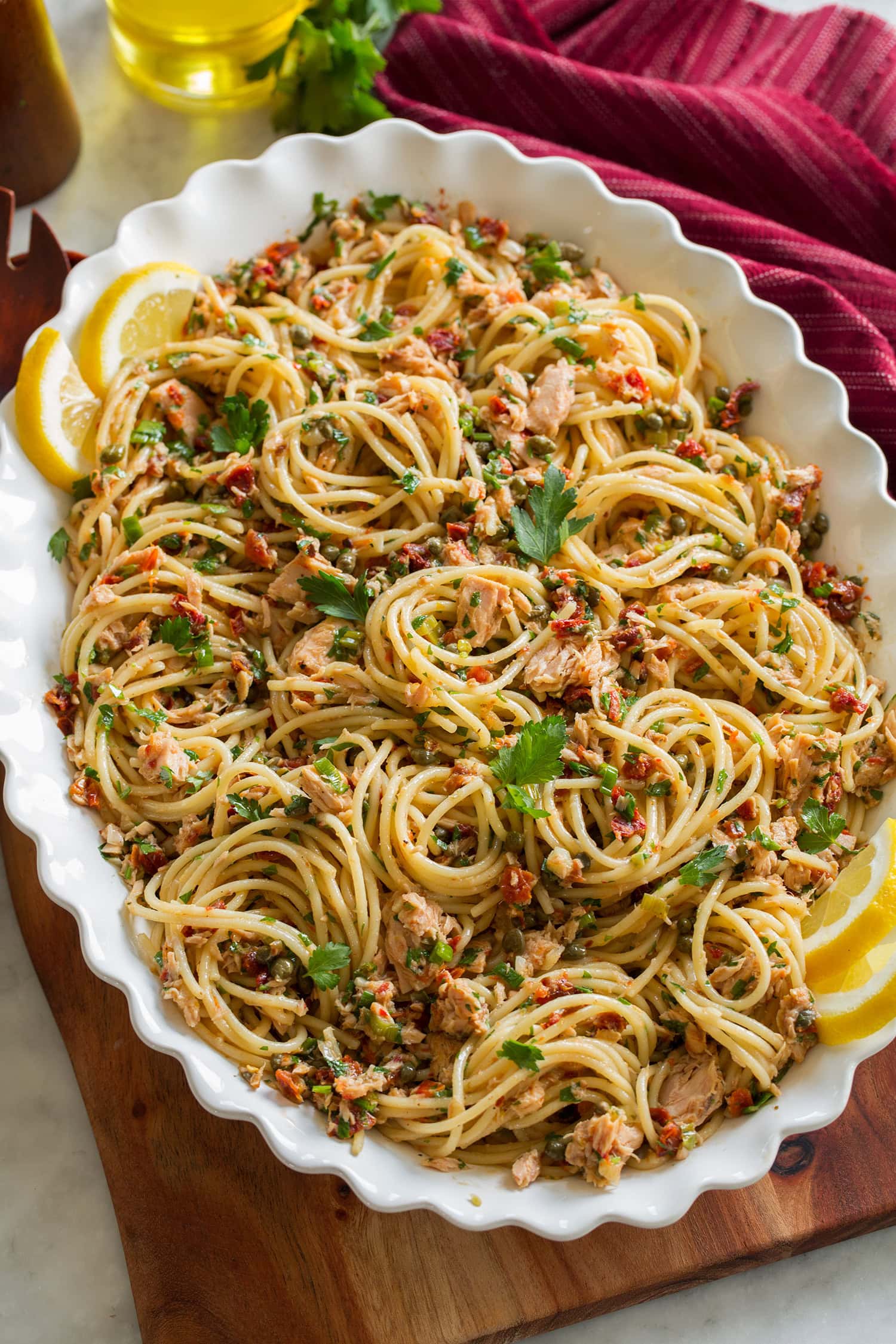 Tuna Pasta Tuna spaghetti in a white serving bowl on a decorative wooden serving tray.
