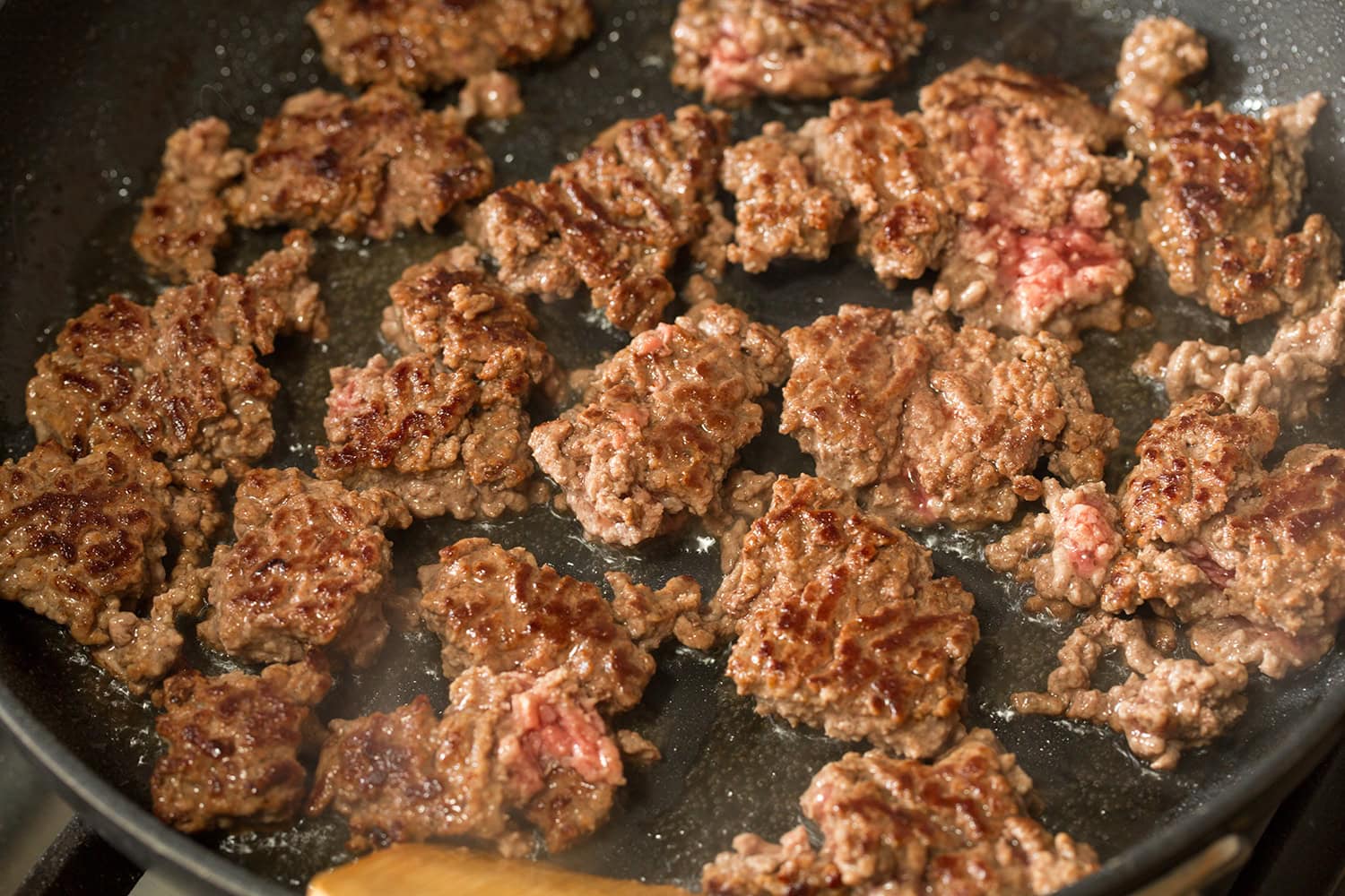 Easy Beef Burritos Ground beef chunks in skillet shown after turning showing nicely browned side.