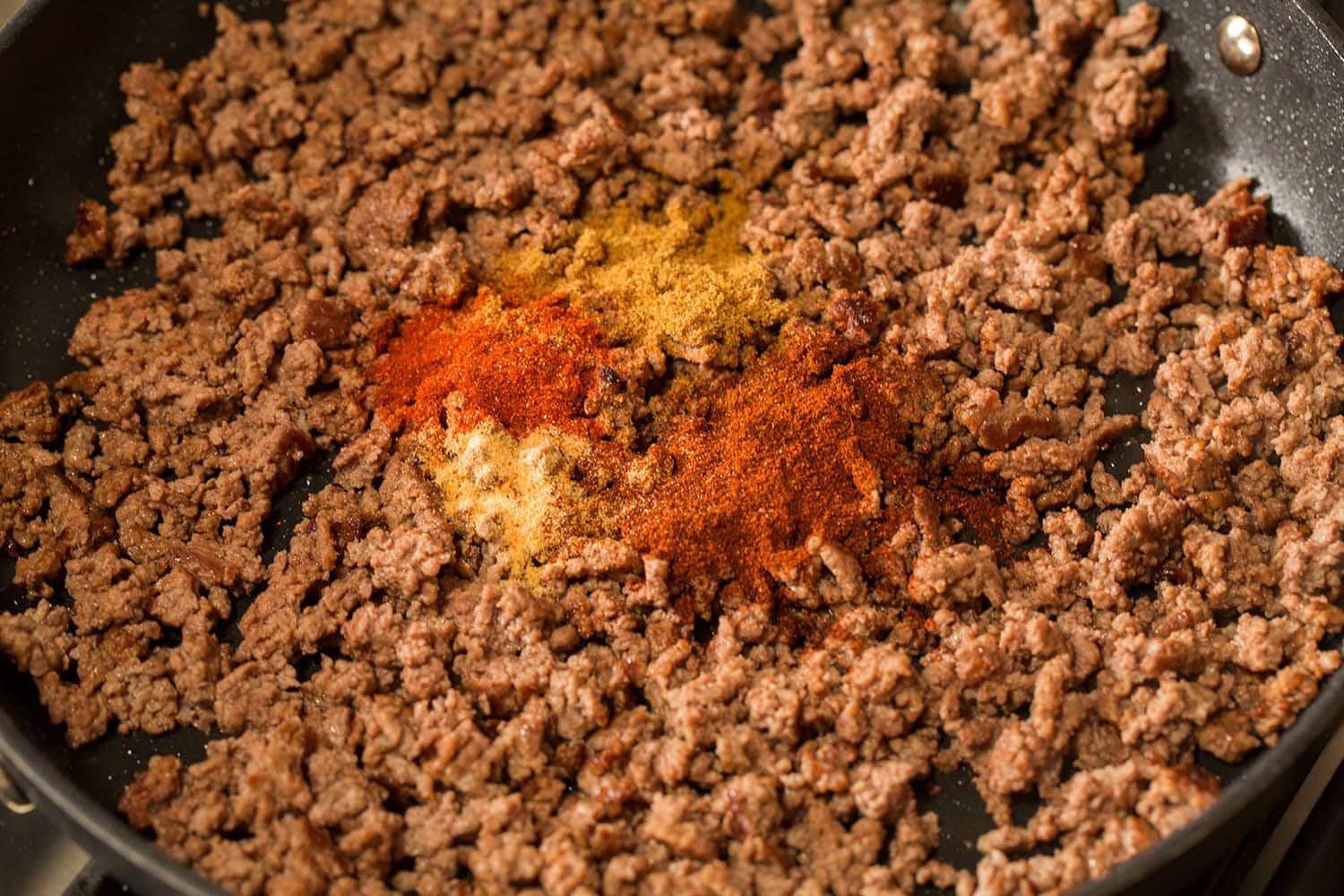 Easy Beef Burritos Mexican spices added to browned beef in a skillet.