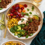 Overhead photo of ground beef fajita bowls with rice, bell peppers, avocado, and corn.
