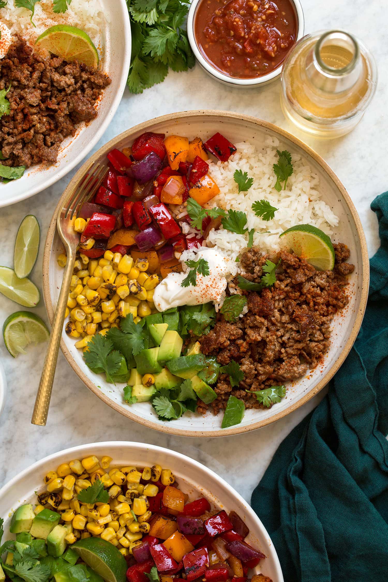 Overhead photo of ground beef fajita bowls with rice, bell peppers, avocado, and corn.