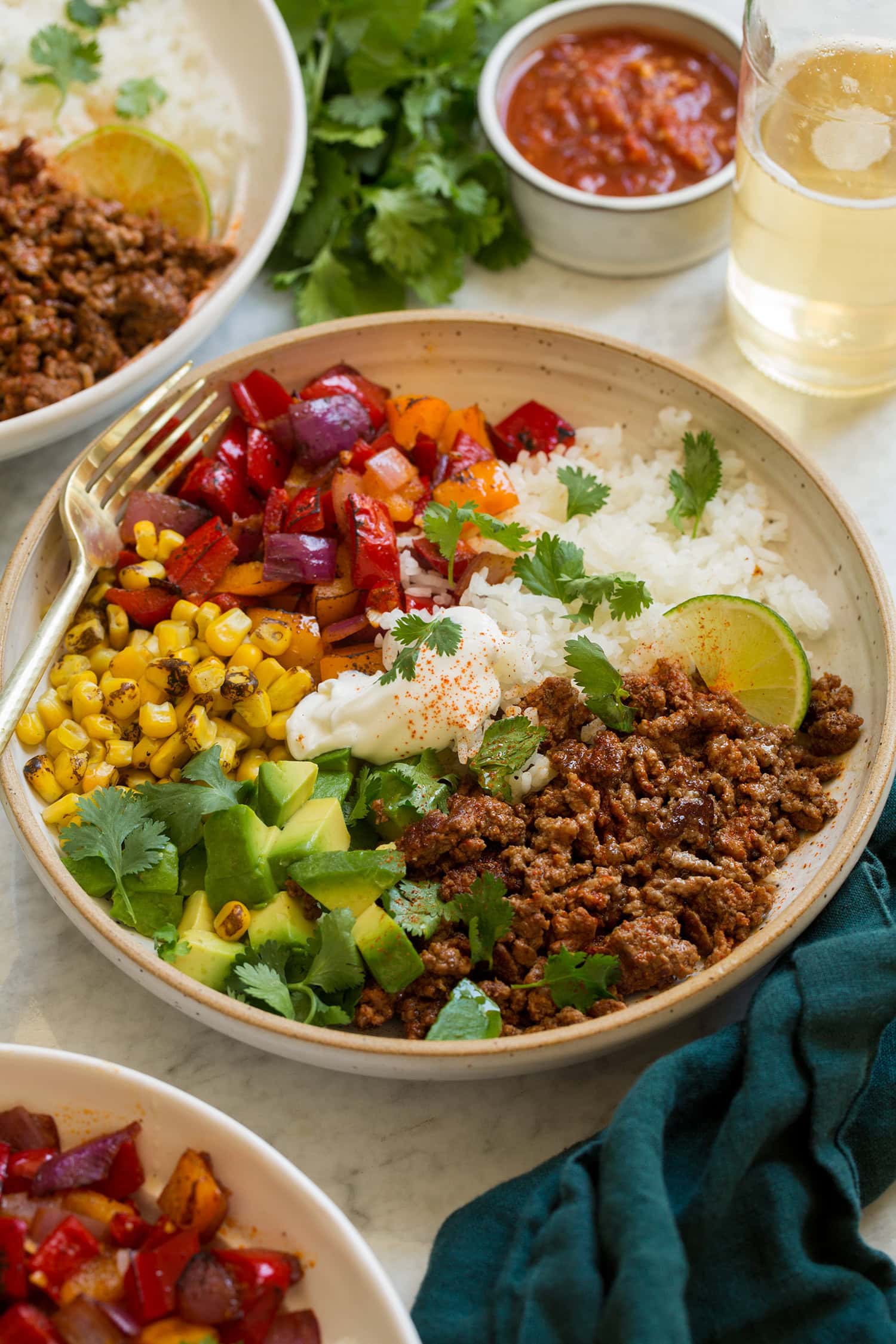 Fajita bowls with white rice, seasoned ground beef, bell peppers, corn, cilantro and it's topped with sour cream.