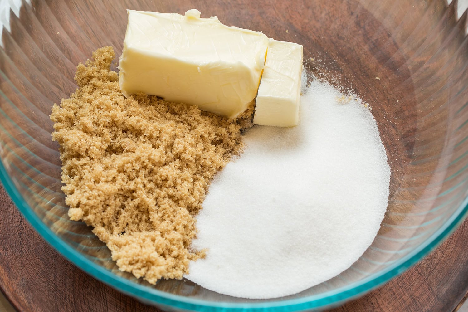 Softened butter, brown sugar and white sugar in glass mixing bowl before mixing.