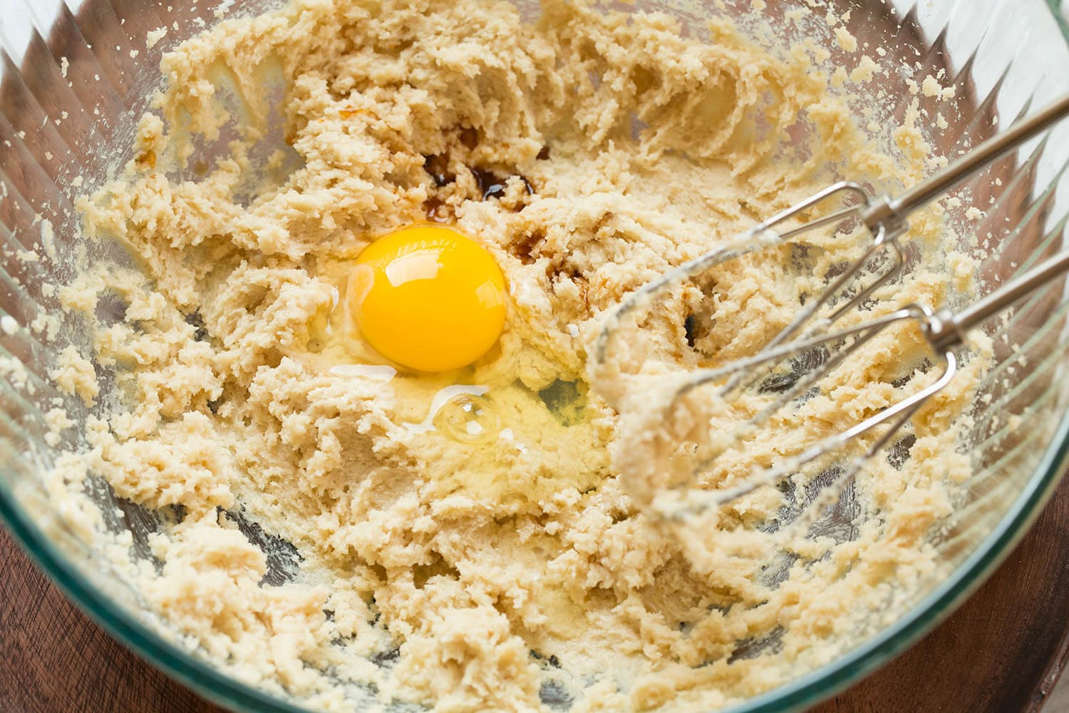 Egg and vanilla added to creamed butter and sugar mixture in mixing bowl.