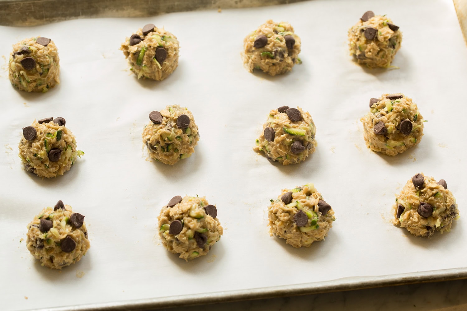 Zucchini oat cookie dough balls on baking sheet shown before baking.