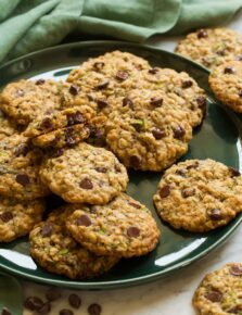 Large green plate with zucchini oatmeal chocolate chip cookies layered on it.
