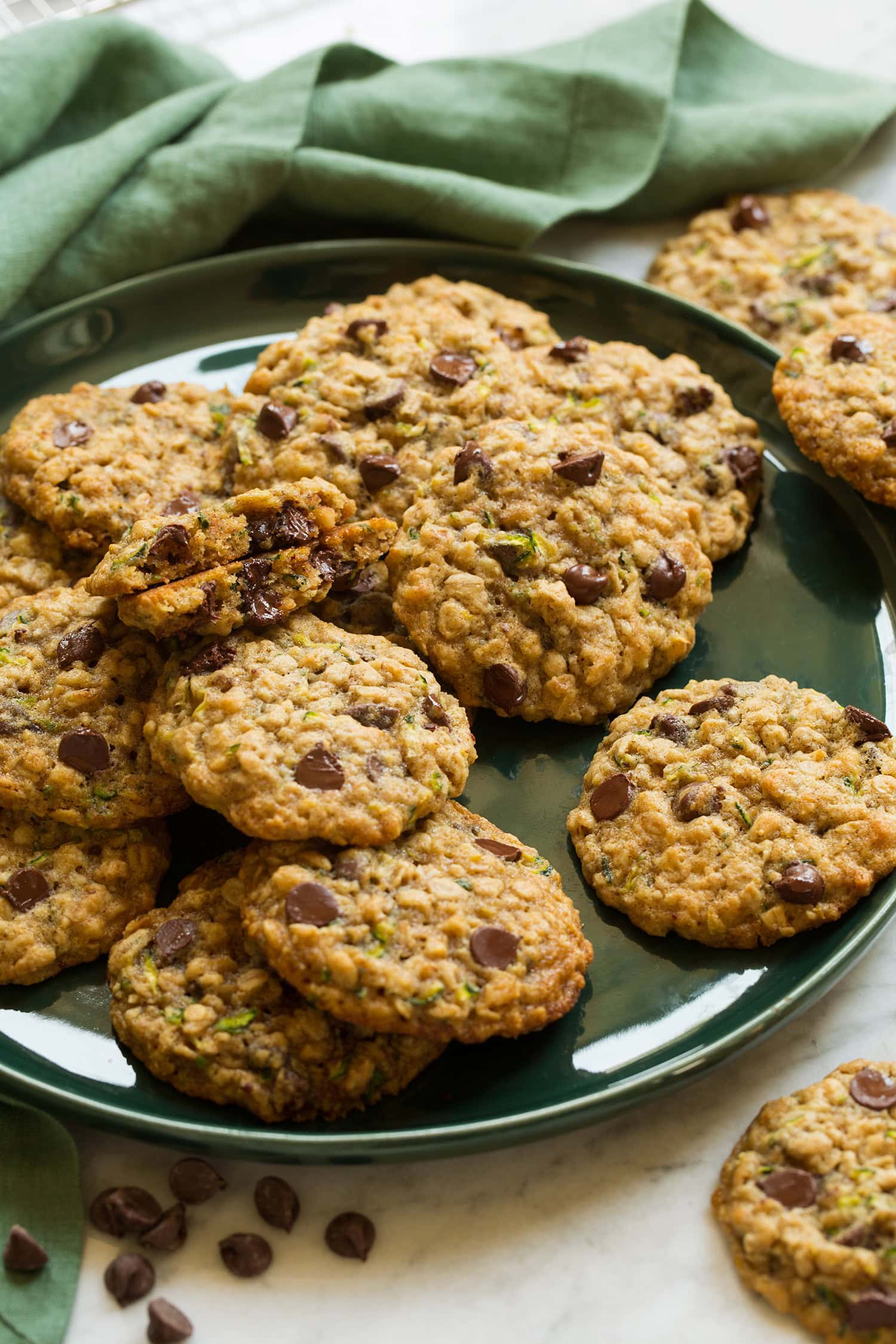 Large green plate with zucchini oatmeal chocolate chip cookies layered on it.