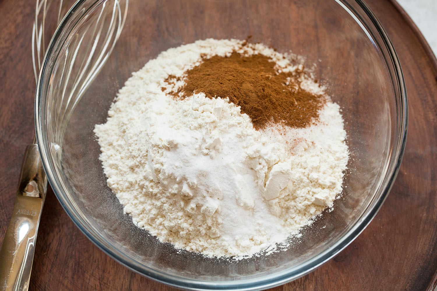 Flour, baking soda, salt and cinnamon in glass mixing bowl before mixing.
