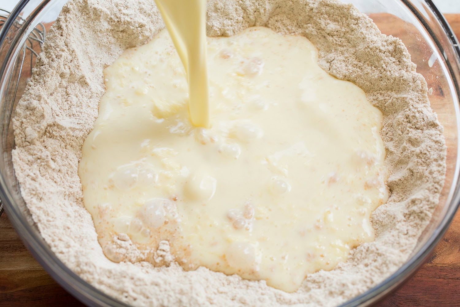Cinnamon Roll Pancakes Milk mixture being poured into dry cinnamon pancake mixture.